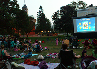 Group of people in Memorial park on blankets and chairs watching film